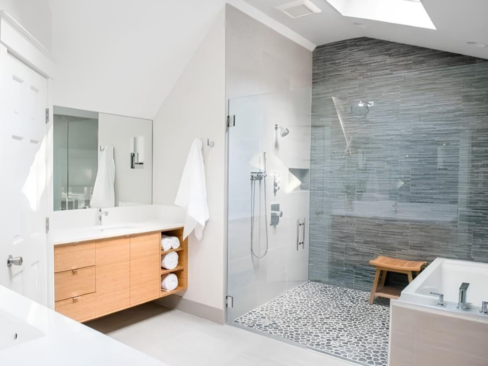 Bright bathroom remodel with an oversized curbless glass shower with a skylight above by Creekstone Design + Remodel in Portland, OR