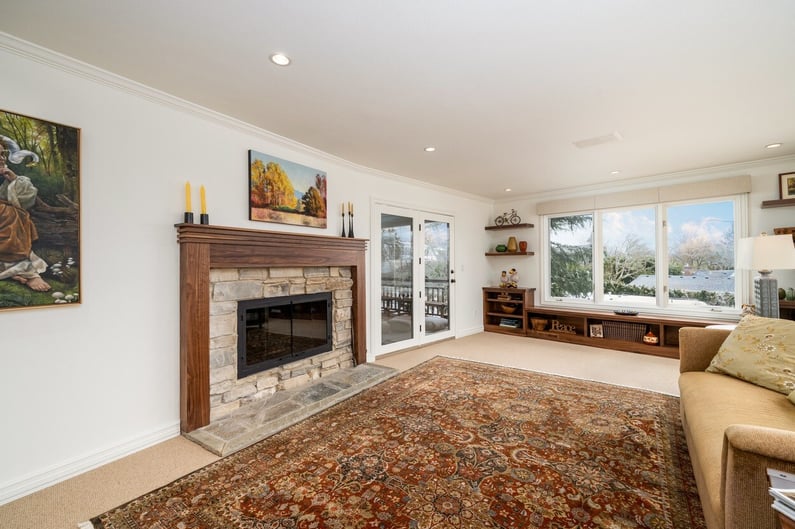 Cozy living room with stone fireplace and large picture window in a whole home remodel in Portland, OR by Creekstone Design + Remodel
