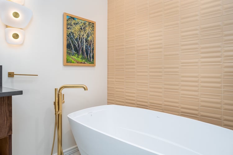 Modern bathroom design featuring a dark stone vanity, gold faucet, and stylish lighting, included in a whole home remodel in Portland, OR by Creekstone Design + Remodel