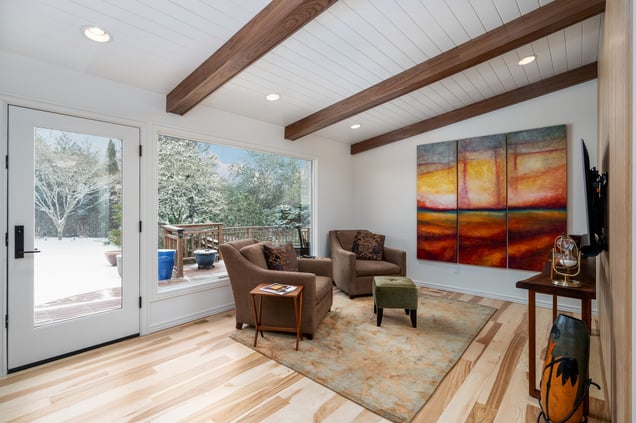 Renovated den featuring warm wood accents, modern seating, and a large abstract painting, designed for a whole home remodel in Portland, OR by Creekstone Design + Remodel