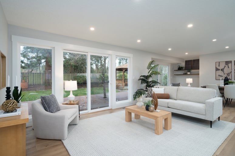 Bright living room with sliding glass doors and modern neutral décor in a whole home remodel by Creekstone Design + Remodel in Raleigh Hills, OR