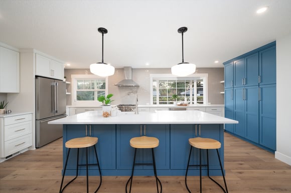 Open kitchen with bold blue island and pendant lighting in a whole home remodel by Creekstone Design + Remodel in Raleigh Hills, OR