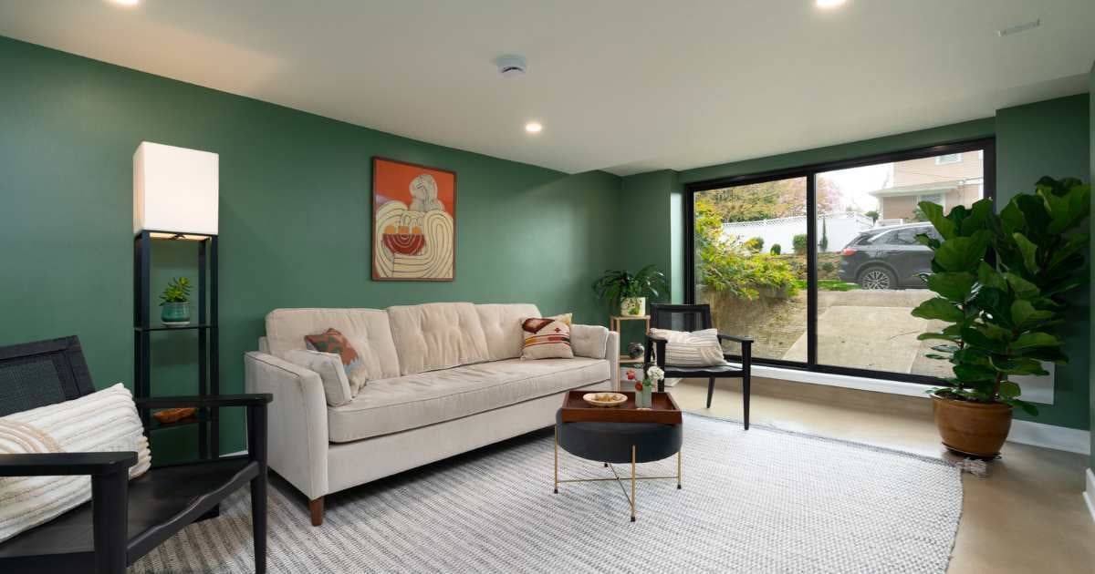 Image of basement remodel seating area with sofa, chair, side table, and large window in Rose City Park
