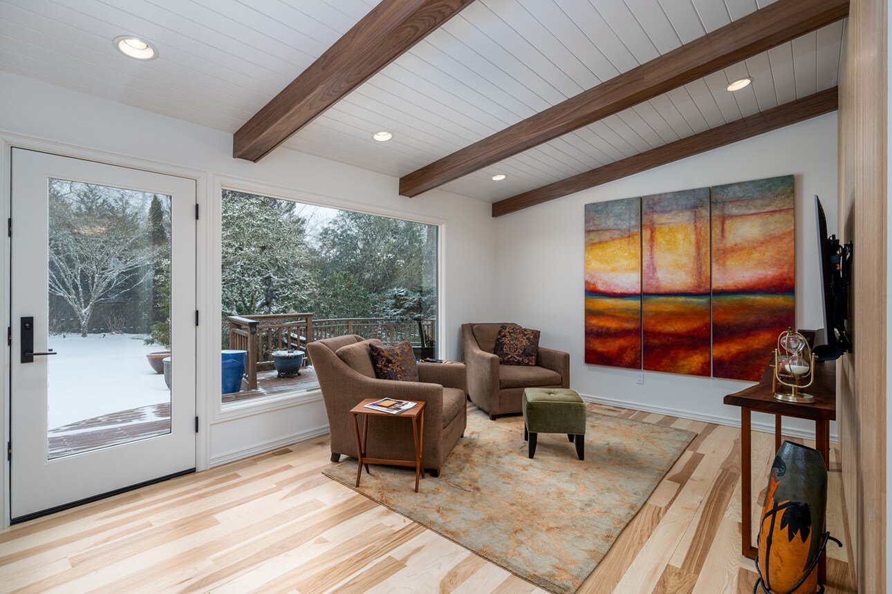 Renovated den featuring warm wood accents, modern seating, and a large abstract painting, designed for a whole home remodel in Portland, OR by Creekstone Design + Remodel