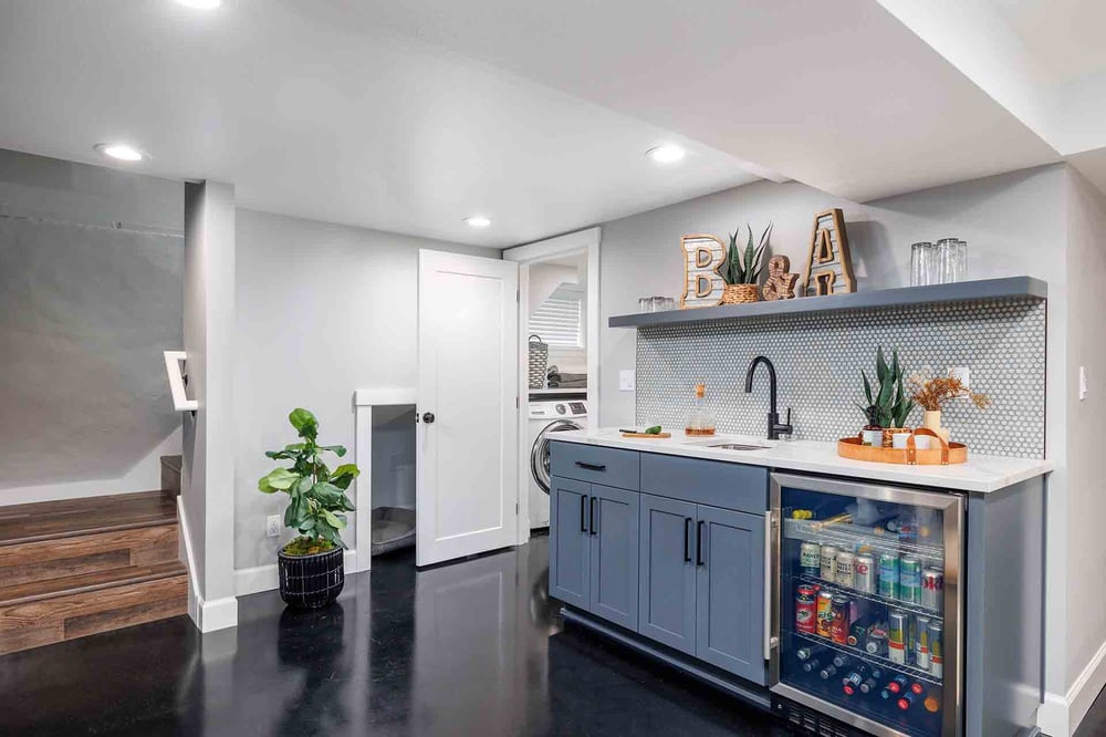 Custom basement kitchenette with a sink, cabinetry, and a beverage refrigerator