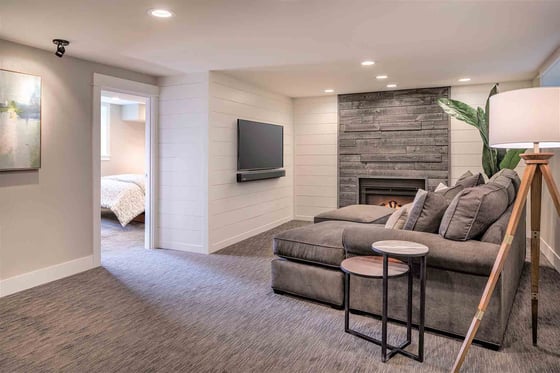 Custom remodeled basement entertainment area featuring a fireplace and mounted TV by Creekstone Design + Remodel in Portland, OR