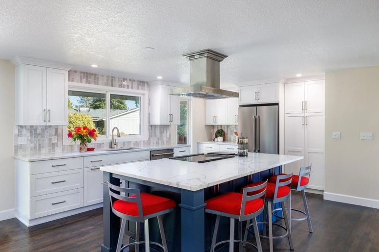Remodeled kitchen with grey and white backsplash featuring a large kitchen island with barstool seating by Creekstone Design + Remodel