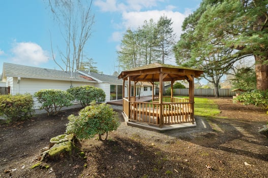 Rear view of home and gazebo framed by mature landscaping in the Raleigh Hills whole home remodel by Creekstone Design + Remodel in Portland, OR