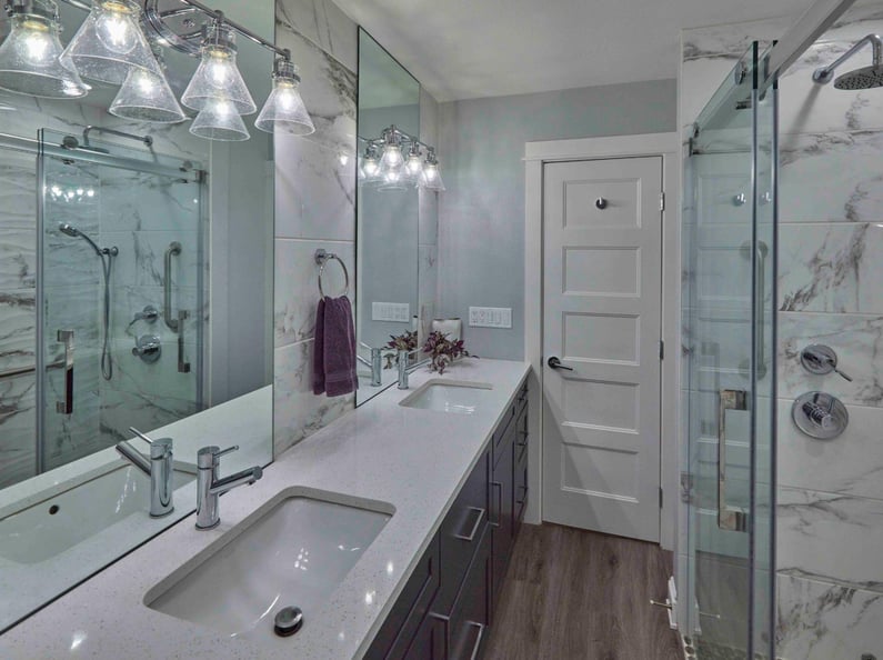 Remodeled basement bathroom view of jack and jill sinks, with partial view of walk-in shower in Tigard, OR by Creekstone Design + Remodel