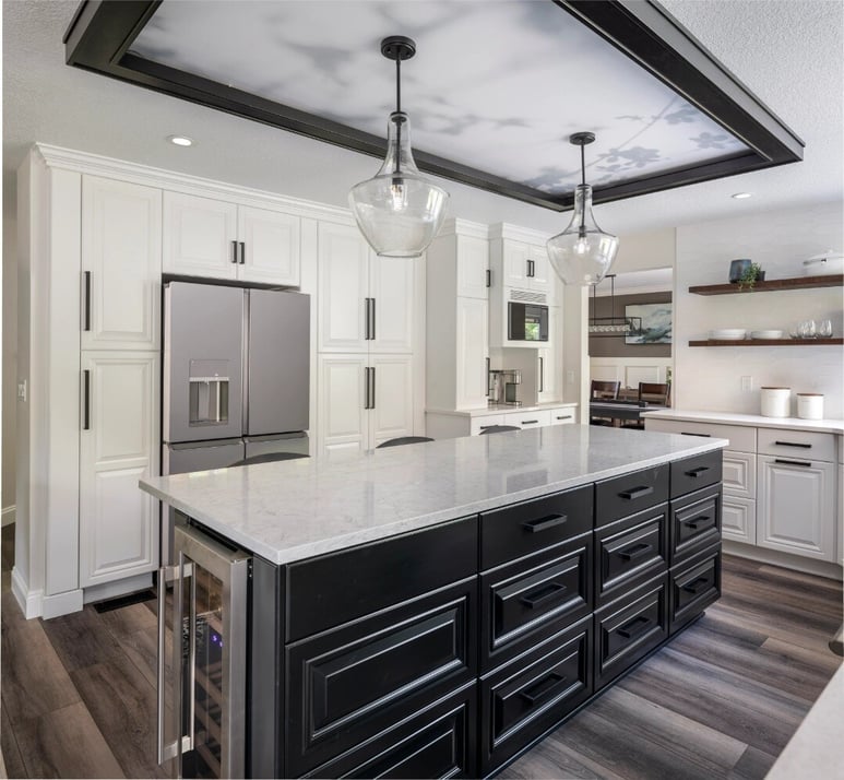 Remodeled kitchen with white cabinetry featuring a kitchen island with built-in wine fridge and black storage by Creekstone Design + Remodel