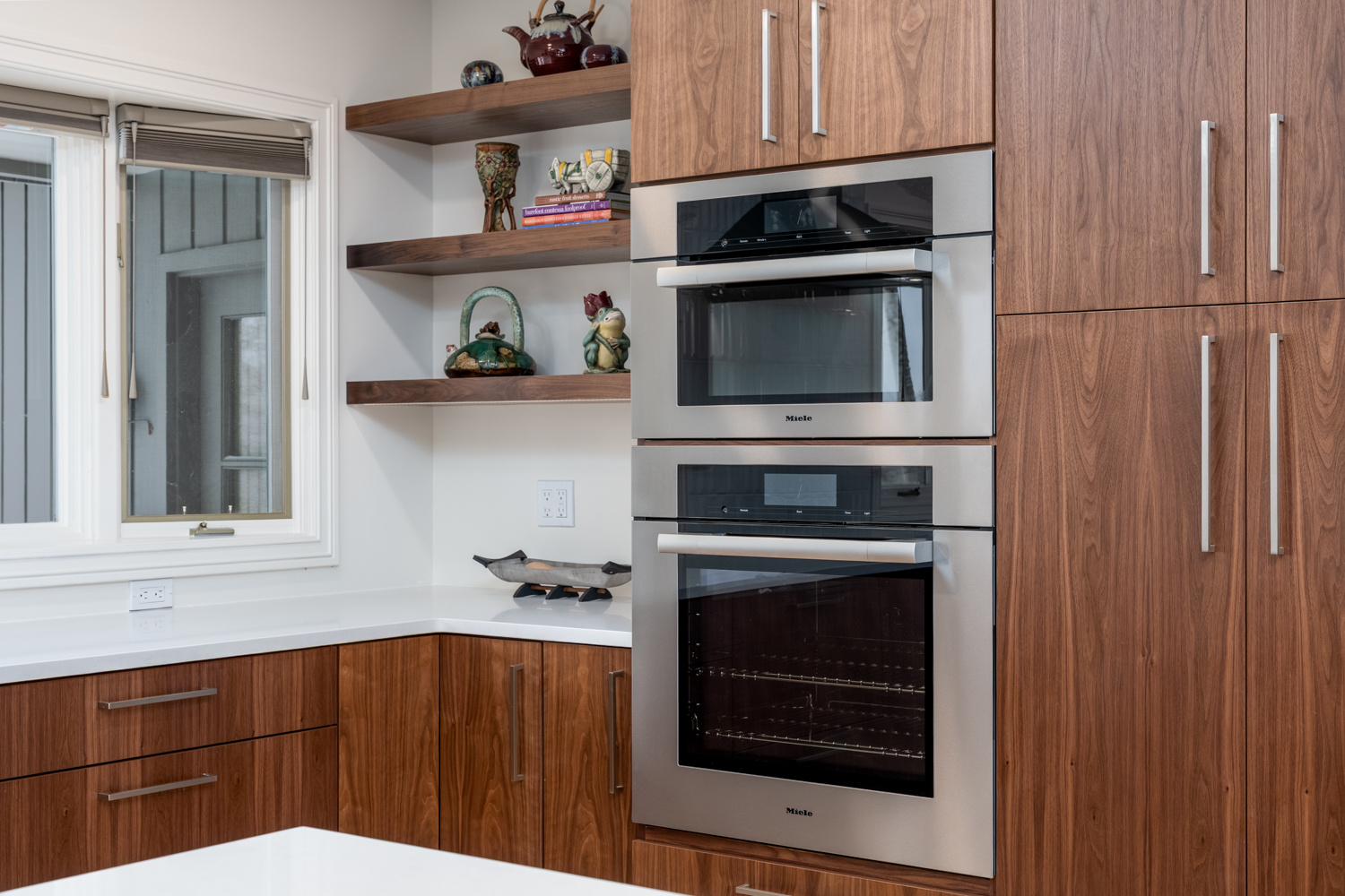 A corner of a contemporary kitchen showcasing double stainless steel ovens, open shelving, and warm wood cabinetry, part of a whole home remodel in Portland, OR by Creekstone Design + Remodel