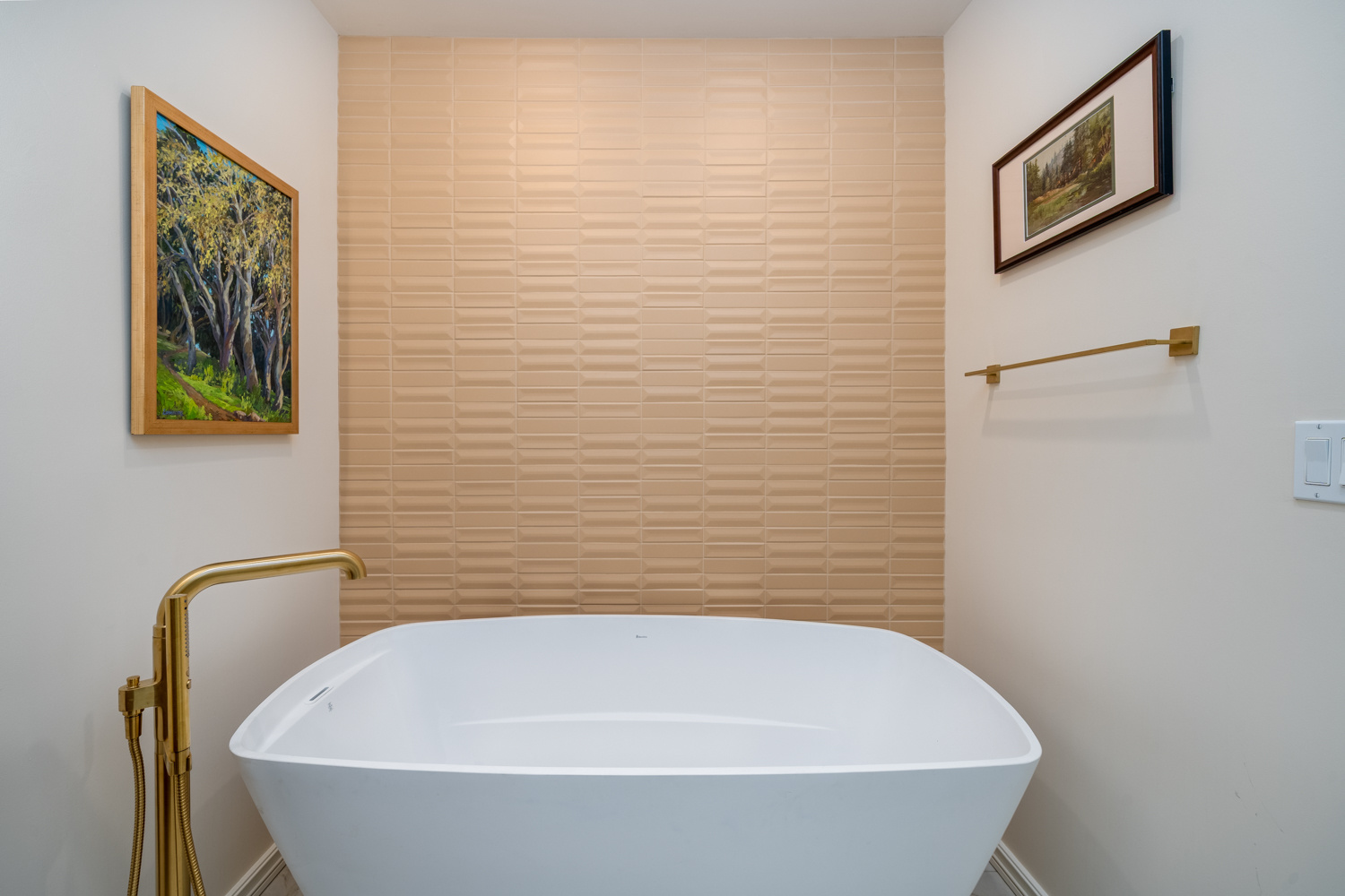 Bathroom with a white freestanding tub, gold fixtures, and textured wall tiles, part of a whole home remodel in Portland, OR by Creekstone Design + Remodel