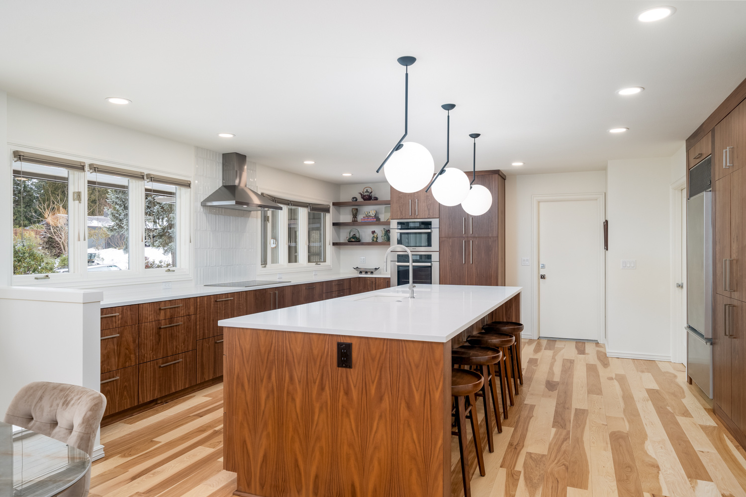 Bright kitchen with white countertops, walnut cabinets, and pendant lighting, part of a whole home remodel in Portland, OR by Creekstone Design + Remodel