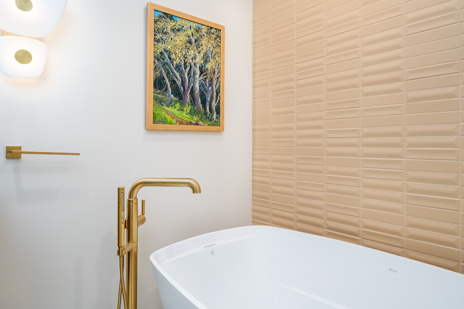 Close-up of a stylish bathroom with a freestanding tub, gold fixtures, and an artful wall design, part of a whole home remodel in Portland, OR by Creekstone Design + Remodel