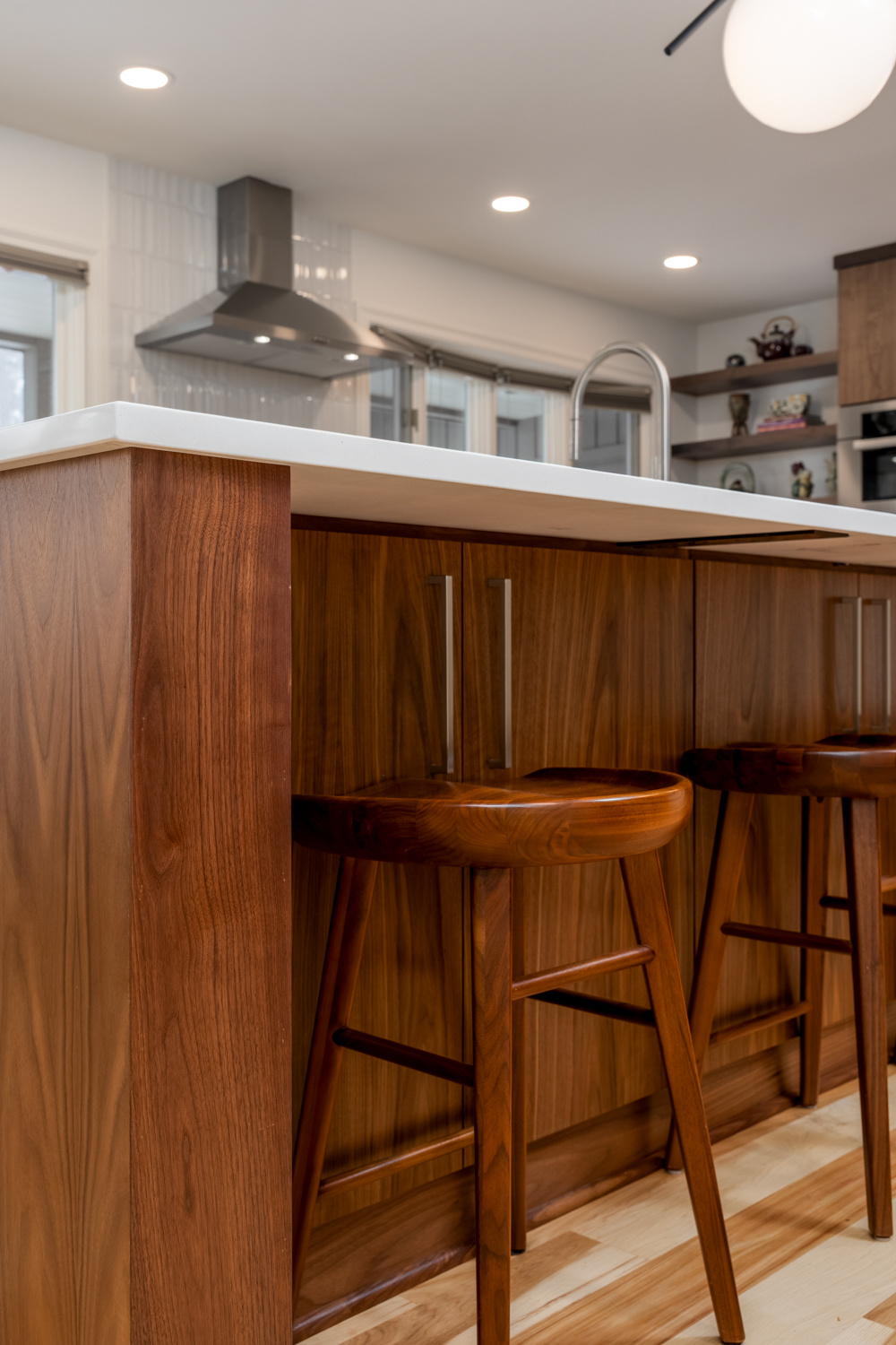 Close-up view of a modern wood kitchen island with barstools, highlighting fine craftsmanship in a whole home remodel in Portland, OR by Creekstone Design + Remodel