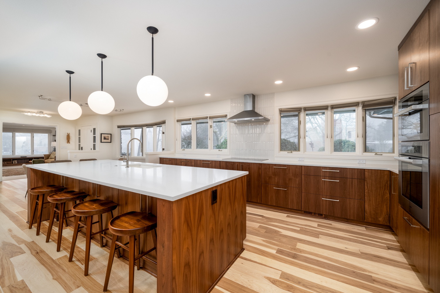 Contemporary kitchen featuring a white quartz island, warm wood cabinetry, and stylish lighting in a whole home remodel in Portland, OR by Creekstone Design + Remodel