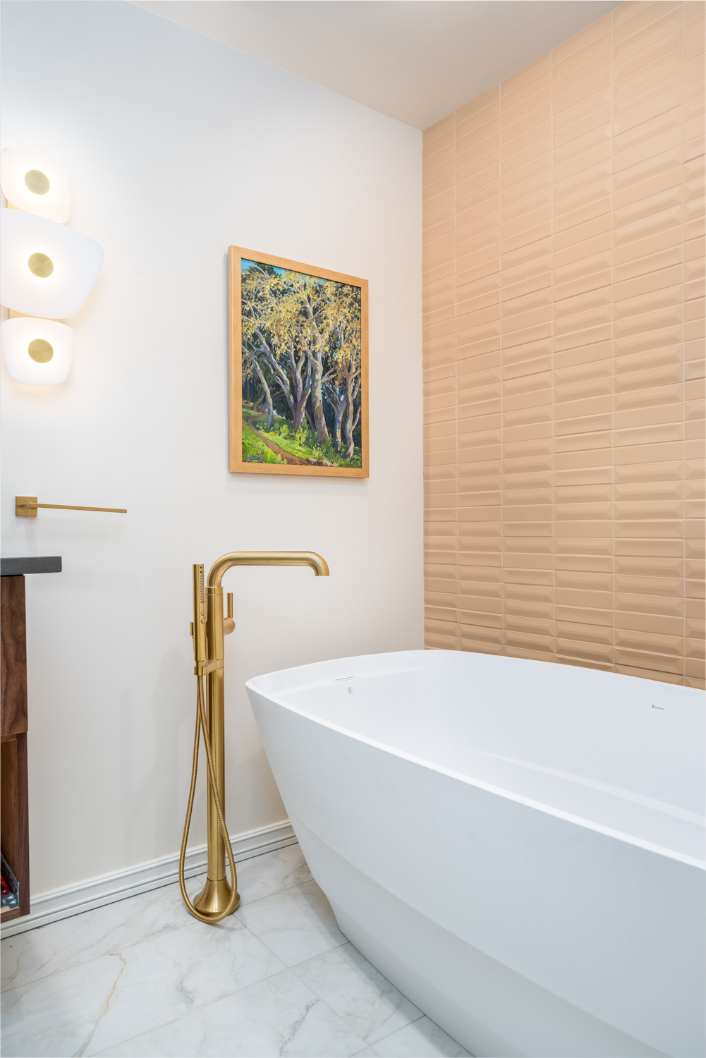 Elegant freestanding bathtub against a warm-toned feature wall with gold accents, featured in a whole home remodel in Portland, OR by Creekstone Design + Remodel