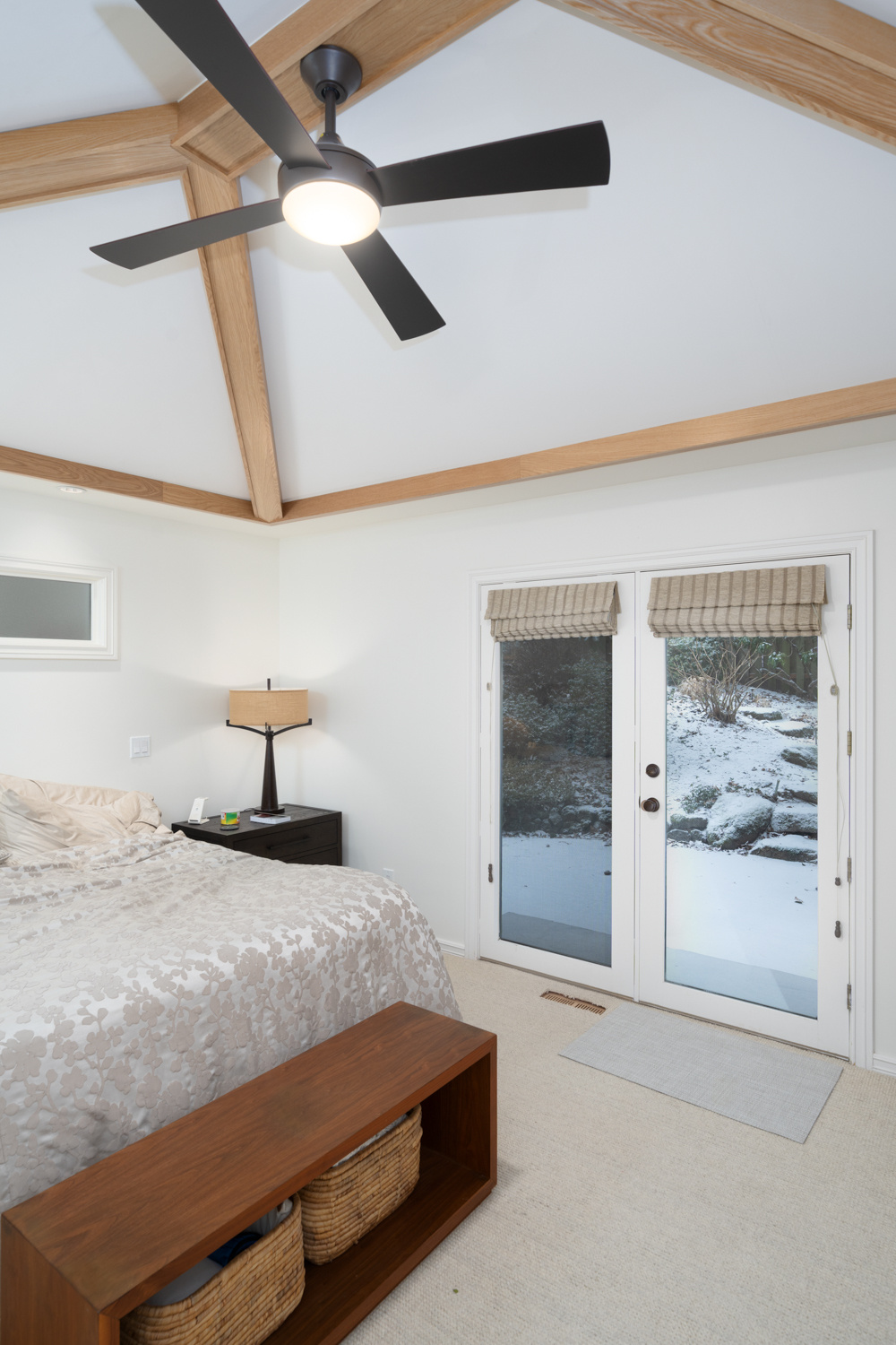 Modern bedroom with vaulted ceiling, exposed wood beams, and a black ceiling fan, part of a whole home remodel in Portland, OR by Creekstone Design + Remodel