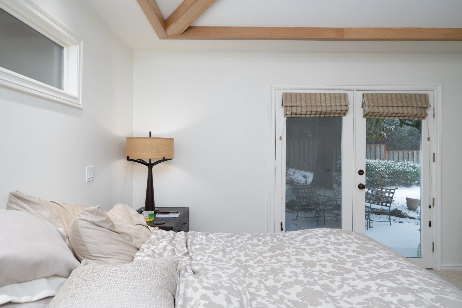 Modern rustic bedroom with exposed wood beams, a neutral color palette, and natural light, included in a whole home remodel in Portland, OR by Creekstone Design + Remodel