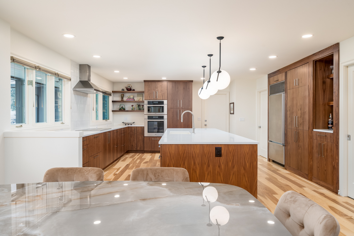 Open-concept kitchen and dining space with warm wood finishes, statement pendant lighting, and stainless steel appliances, part of a whole home remodel in Portland, OR by Creekstone Design + Remodel