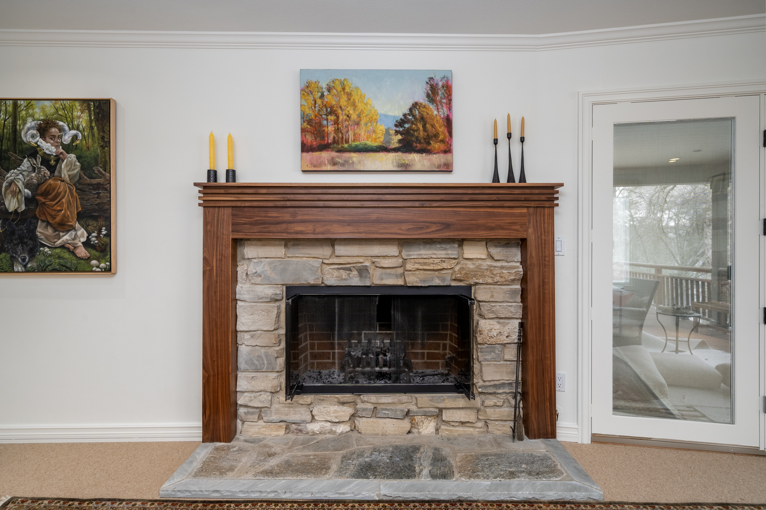 Rustic stone fireplace with a custom wood mantel and artistic wall decor, featured in a whole home remodel in Portland, OR by Creekstone Design + Remodel