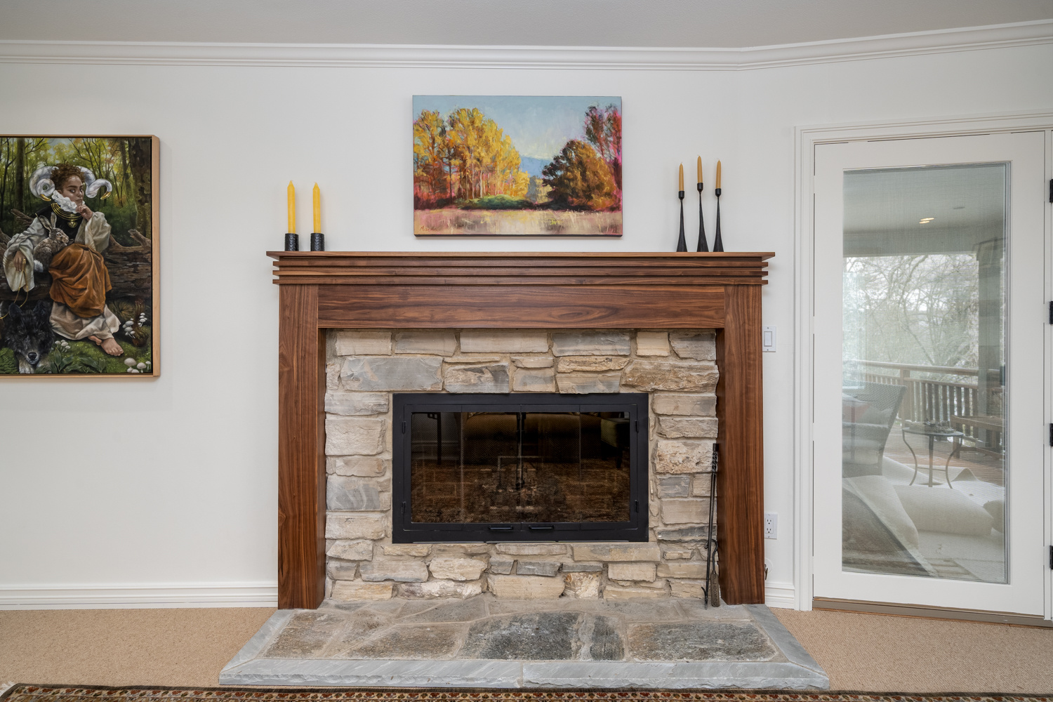 Rustic stone fireplace with a custom wood mantel, framed by elegant decor, part of a whole home remodel in Portland, OR by Creekstone Design + Remodel