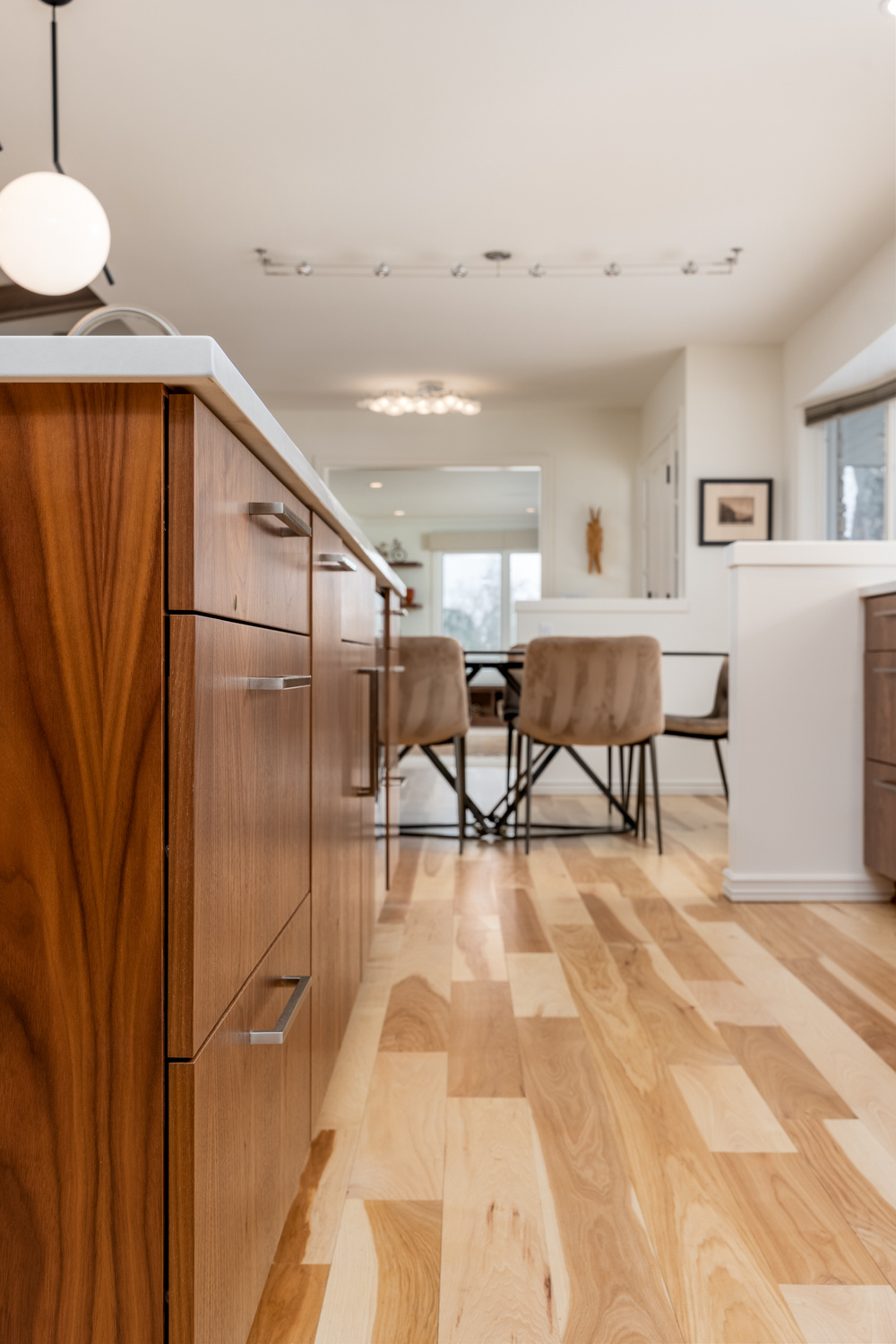 Side view of a spacious kitchen with elegant cabinetry, a bright dining space, and warm wood floors, part of a whole home remodel in Portland, OR by Creekstone Design + Remodel