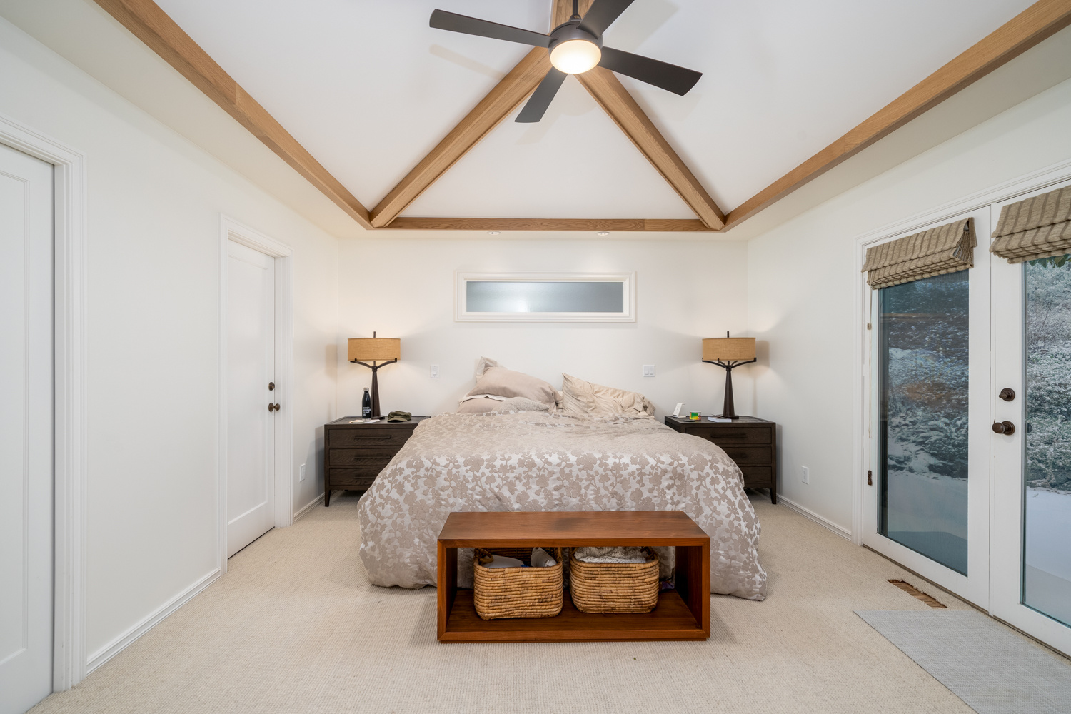Spacious bedroom with a vaulted ceiling, exposed beams, and modern decor, part of a whole home remodel in Portland, OR by Creekstone Design + Remodel