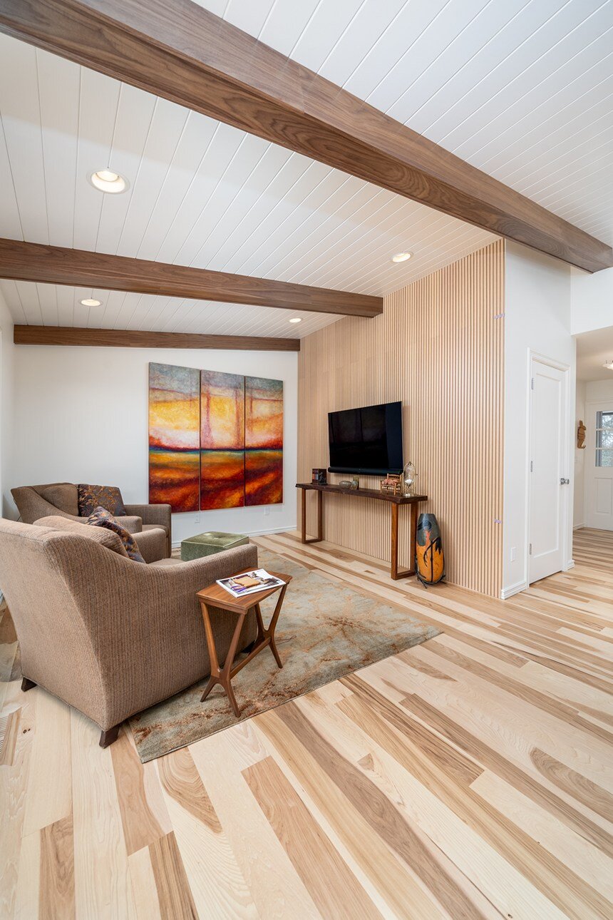 Wide-angle view of a remodeled den with natural wood elements, modern furnishings, and artistic decor in a whole home remodel in Portland, OR by Creekstone Design + Remodel