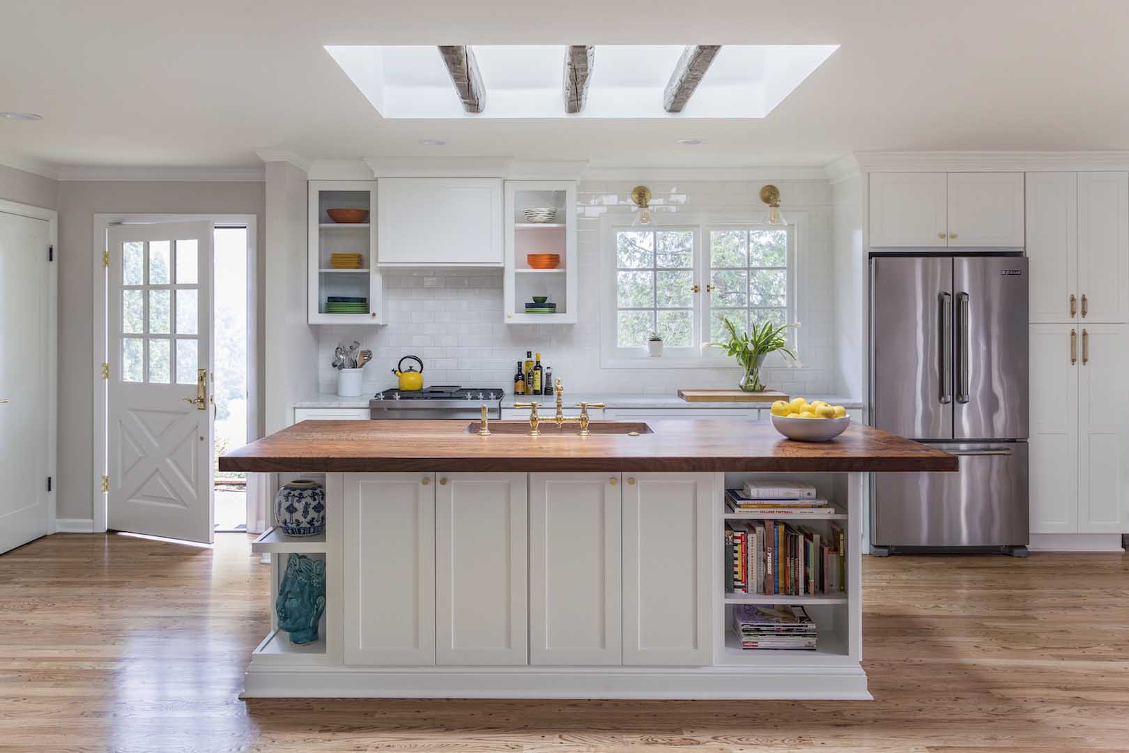 Full kitchen with open shelving, island, and skylight with rustic beams