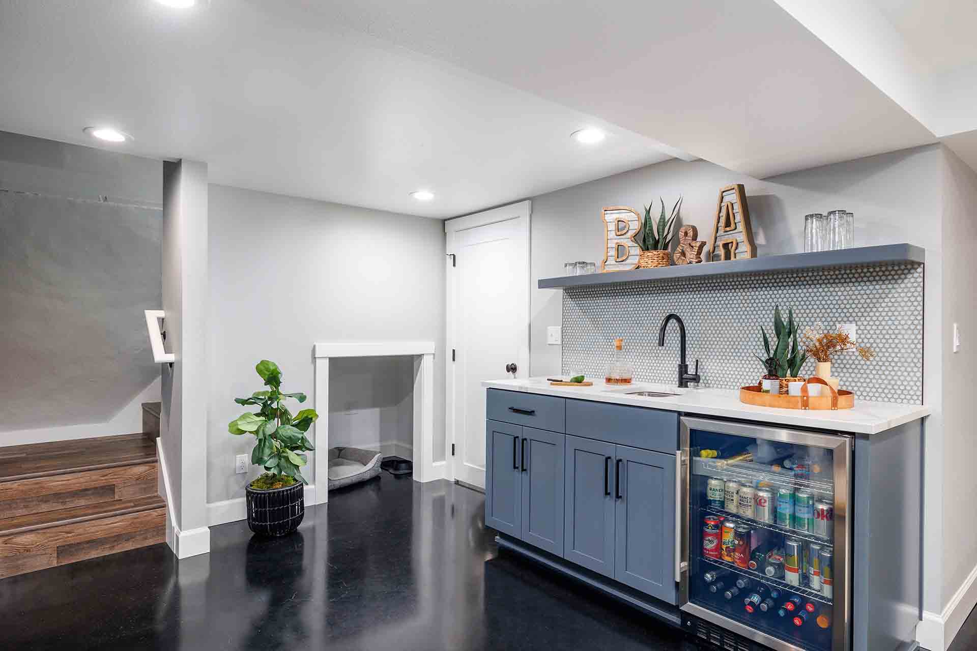 Basement wet bar with blue cabinets and glass door fridge