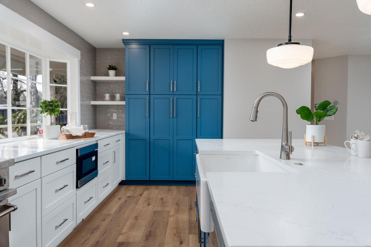 Bright kitchen with bold blue cabinetry and quartz countertops, part of the Raleigh Hills whole home remodel by Creekstone Design + Remodel in Portland, OR